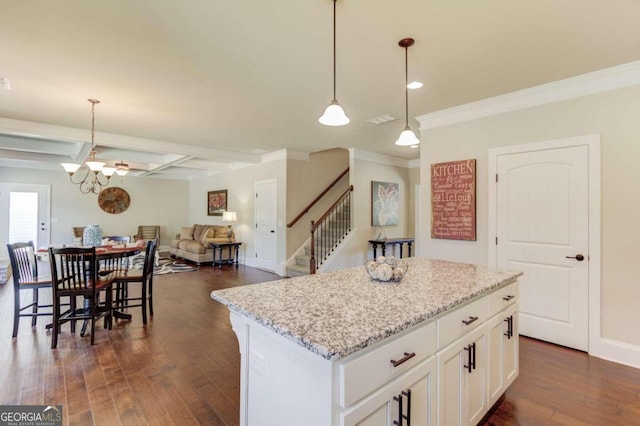 kitchen featuring dark wood-type flooring, a kitchen island, white cabinetry, decorative light fixtures, and crown molding