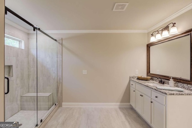 bathroom with a shower with shower door, vanity, and ornamental molding