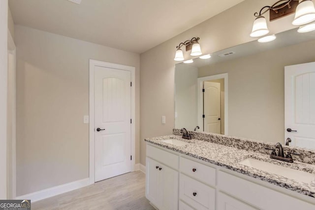 bathroom with hardwood / wood-style flooring and dual vanity