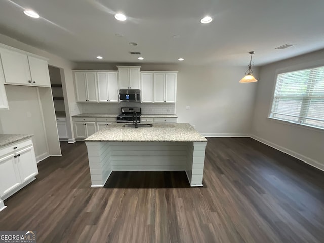 kitchen with light stone counters, white cabinets, and a kitchen island with sink