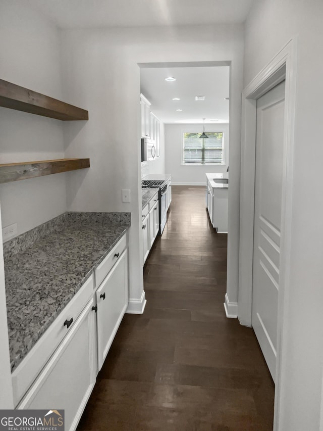 kitchen featuring stone countertops, white cabinetry, dark wood-type flooring, and stainless steel range with gas stovetop