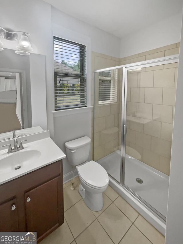 bathroom featuring tile patterned flooring, vanity, a shower with shower door, and toilet