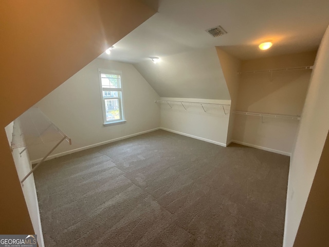 bonus room featuring dark colored carpet and vaulted ceiling