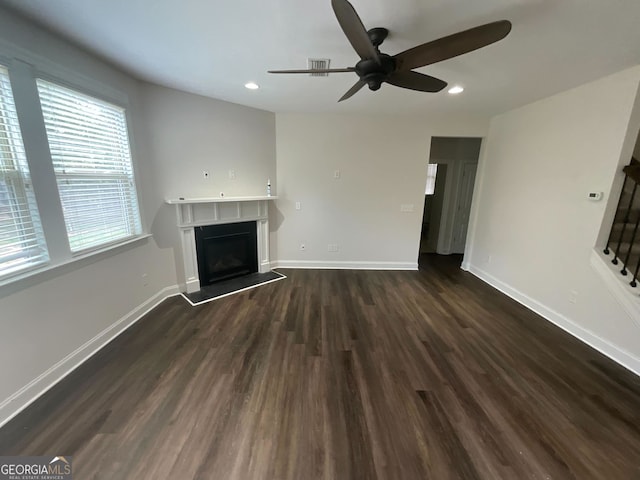 unfurnished living room featuring ceiling fan and dark wood-type flooring