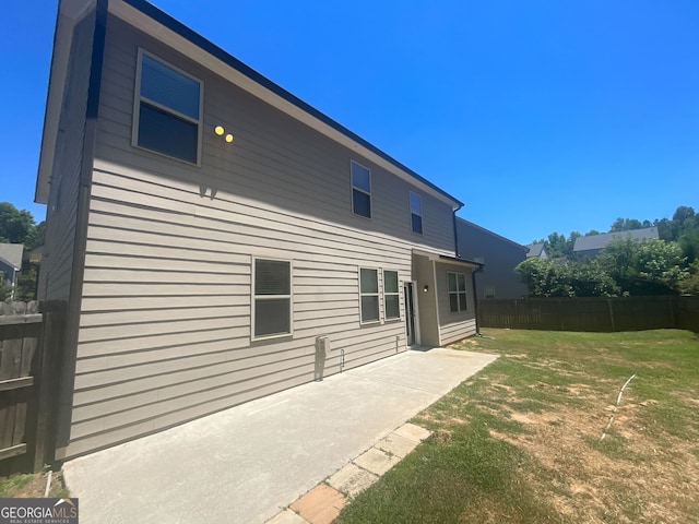 back of house with a patio area and a lawn