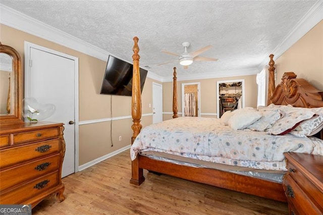 bedroom with ornamental molding, wood-type flooring, ceiling fan, and a textured ceiling