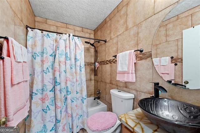 full bathroom with shower / bath combo with shower curtain, tile walls, sink, toilet, and a textured ceiling