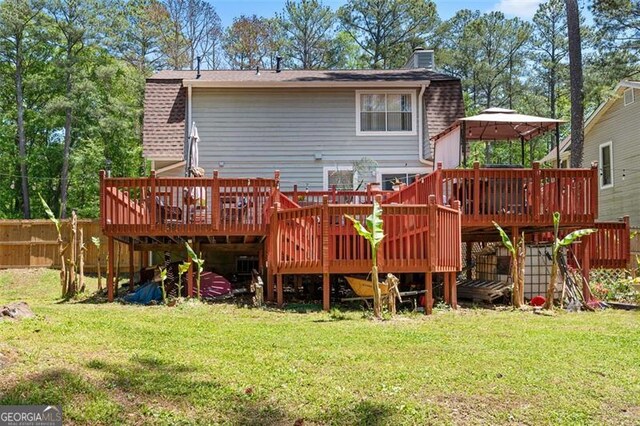 rear view of property with a deck and a lawn