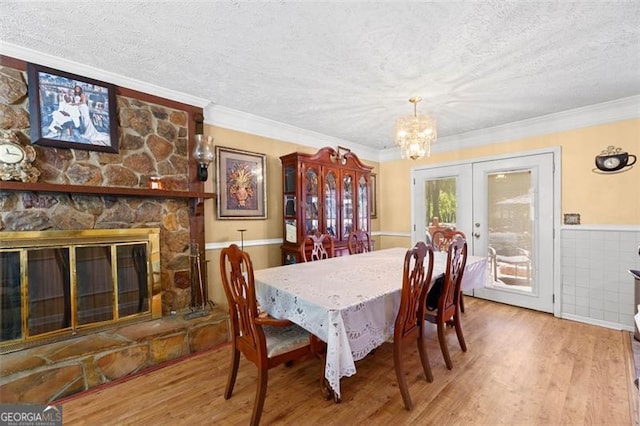 dining area with hardwood / wood-style flooring, ornamental molding, a textured ceiling, and a fireplace