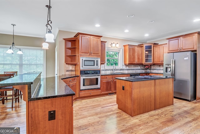 kitchen with sink, decorative backsplash, light hardwood / wood-style floors, a kitchen island, and stainless steel appliances