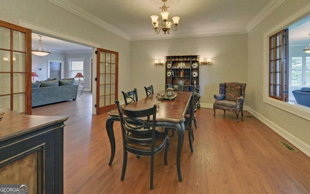 dining room with wood-type flooring, french doors, a notable chandelier, and crown molding