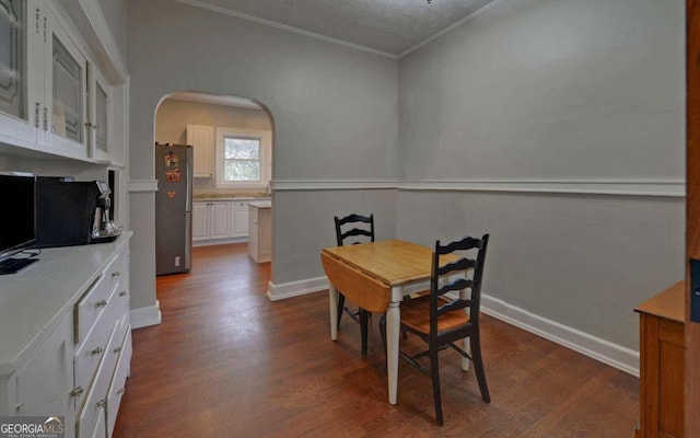 dining space with dark hardwood / wood-style flooring, crown molding, and a textured ceiling