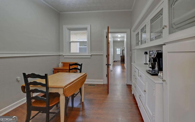 dining room featuring ornamental molding, dark hardwood / wood-style flooring, and a textured ceiling