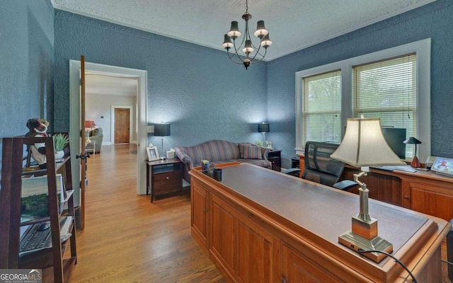 office space featuring ornamental molding, an inviting chandelier, light hardwood / wood-style flooring, and a textured ceiling