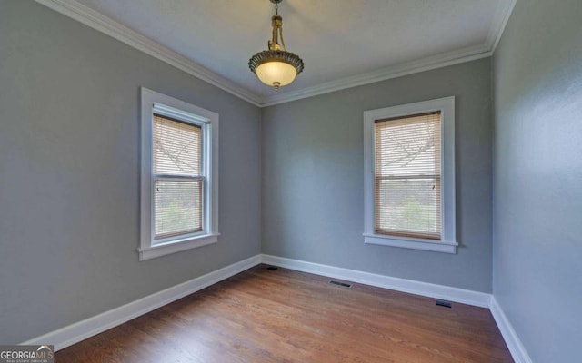 spare room featuring a healthy amount of sunlight, hardwood / wood-style floors, and crown molding