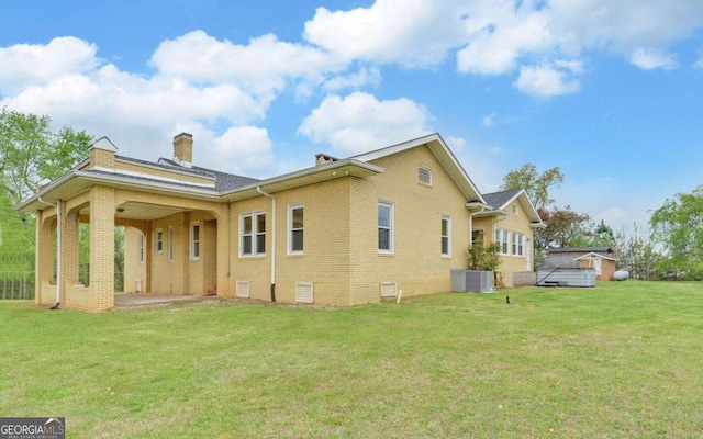 rear view of property featuring a patio, central AC unit, and a lawn