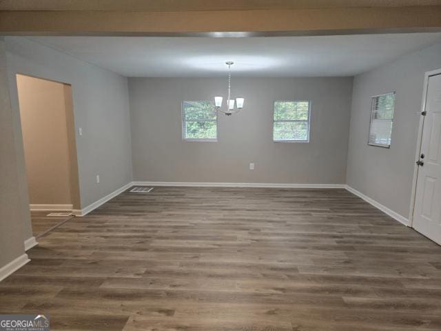 empty room featuring dark hardwood / wood-style flooring and a notable chandelier