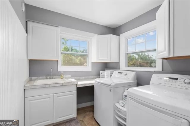 laundry room with a healthy amount of sunlight, sink, separate washer and dryer, and light tile floors