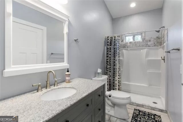 bathroom featuring walk in shower, vanity, tile floors, and toilet