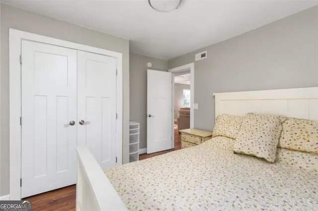 bedroom with dark hardwood / wood-style flooring and a closet