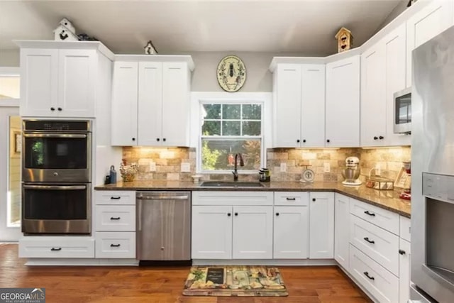 kitchen featuring wood-type flooring, white cabinetry, appliances with stainless steel finishes, sink, and tasteful backsplash