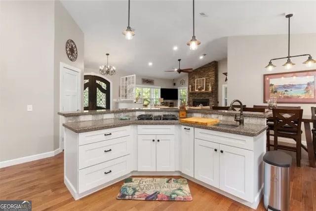 kitchen with lofted ceiling, a fireplace, light hardwood / wood-style floors, and decorative light fixtures