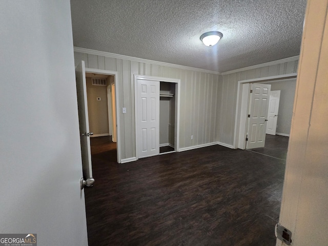 unfurnished bedroom featuring ornamental molding, dark hardwood / wood-style flooring, a closet, and a textured ceiling