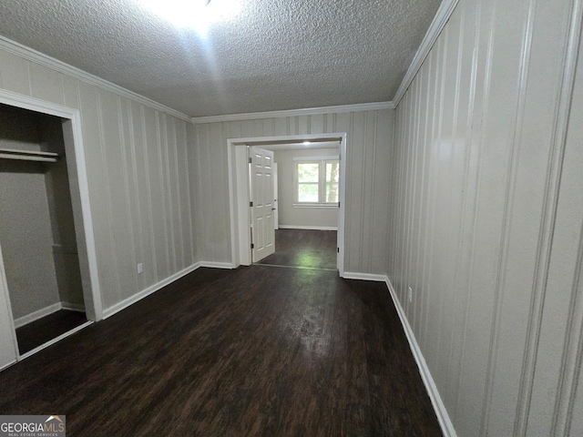 unfurnished bedroom with a closet, a textured ceiling, dark hardwood / wood-style flooring, and ornamental molding