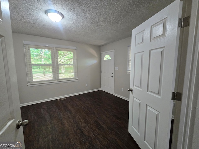 spare room featuring dark hardwood / wood-style floors and a textured ceiling