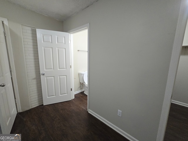 corridor with a textured ceiling and dark wood-type flooring