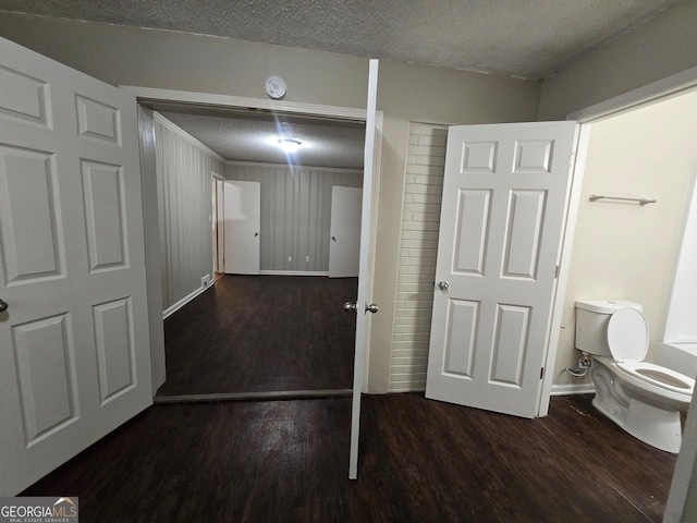 interior space featuring wood-type flooring, toilet, and a textured ceiling