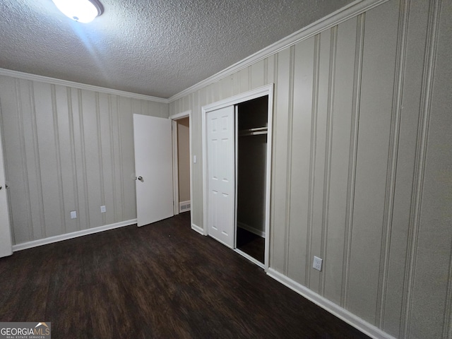 unfurnished bedroom featuring a closet, crown molding, dark hardwood / wood-style floors, and a textured ceiling