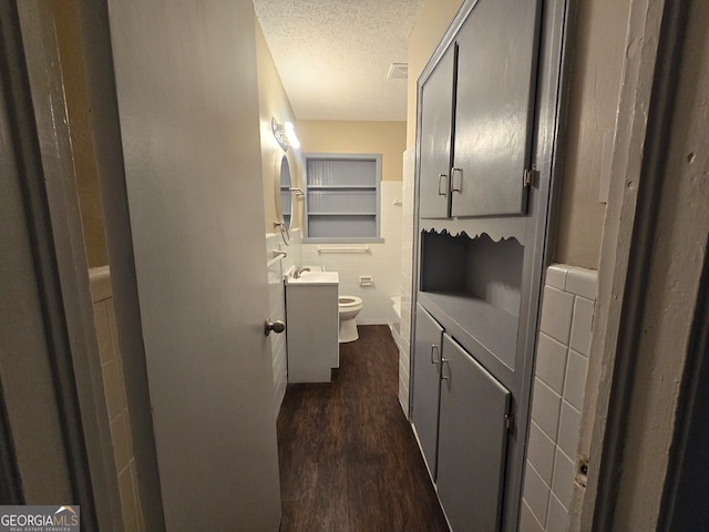 bathroom featuring a textured ceiling, hardwood / wood-style floors, vanity, and toilet