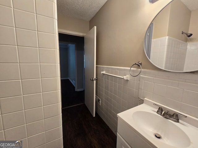 bathroom with vanity, tile walls, hardwood / wood-style floors, backsplash, and a textured ceiling