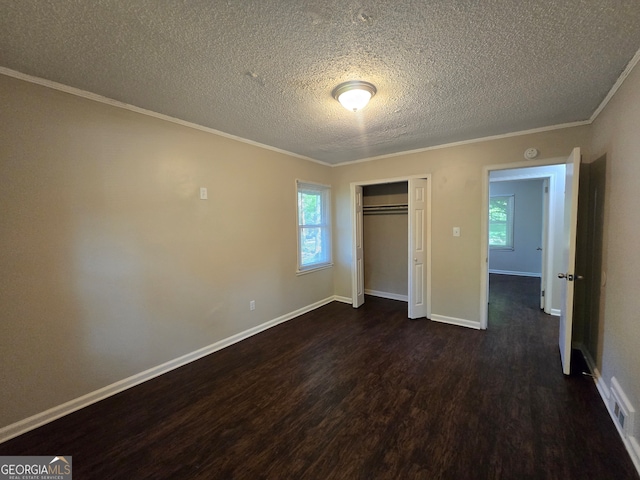 unfurnished bedroom featuring dark hardwood / wood-style flooring, a textured ceiling, and multiple windows