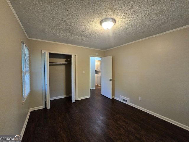 unfurnished bedroom with dark hardwood / wood-style flooring, crown molding, a closet, and a textured ceiling