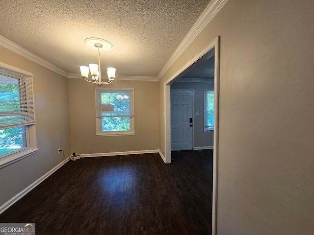 empty room with a textured ceiling, dark hardwood / wood-style flooring, a notable chandelier, and ornamental molding