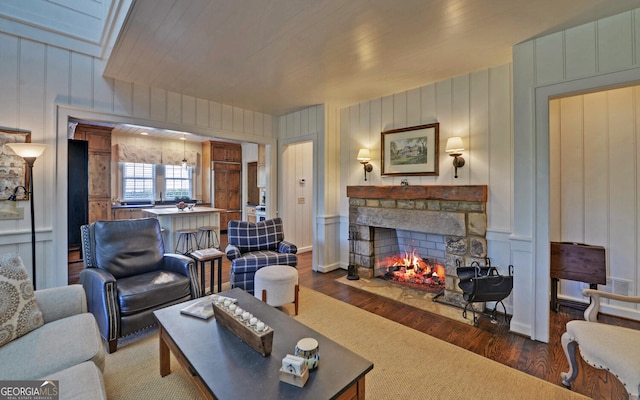 living room featuring a stone fireplace and dark hardwood / wood-style floors