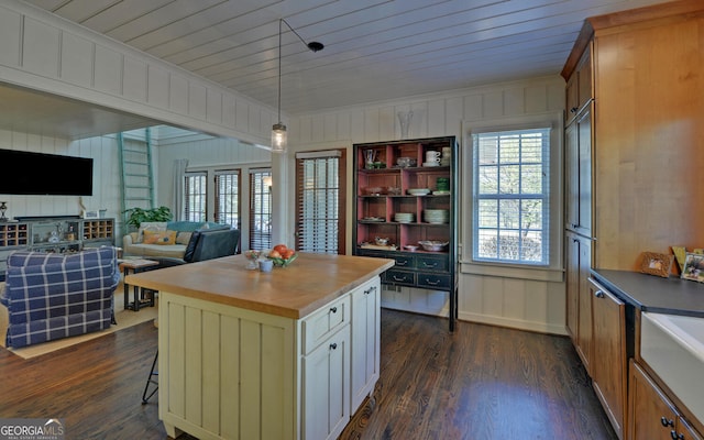 kitchen with wooden counters, dark wood-type flooring, a kitchen bar, a kitchen island, and decorative light fixtures