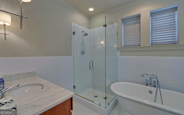 bathroom featuring tile walls, crown molding, vanity, and shower with separate bathtub