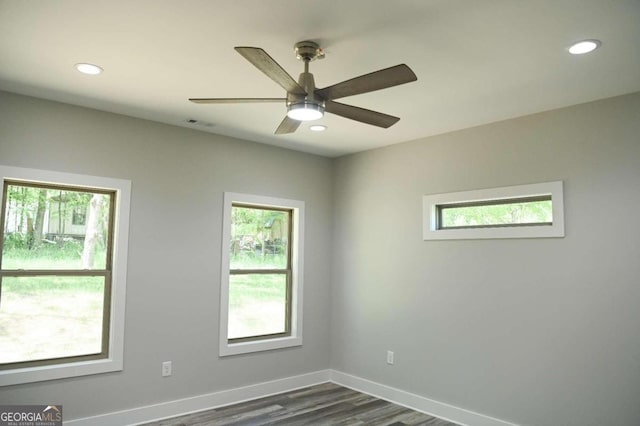 empty room with a healthy amount of sunlight, ceiling fan, and dark hardwood / wood-style floors