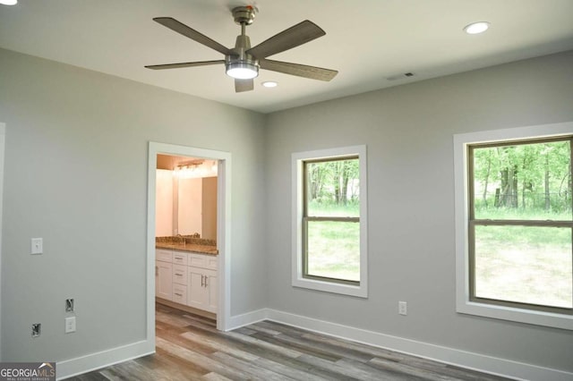 unfurnished bedroom with wood-type flooring, connected bathroom, and ceiling fan