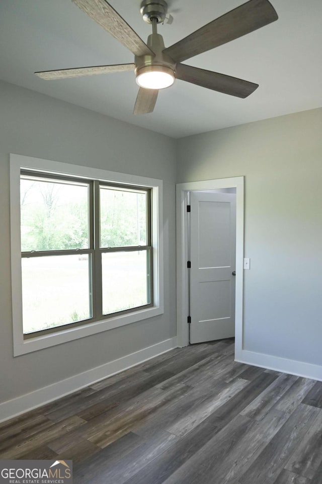 spare room featuring dark wood-type flooring, a wealth of natural light, and ceiling fan