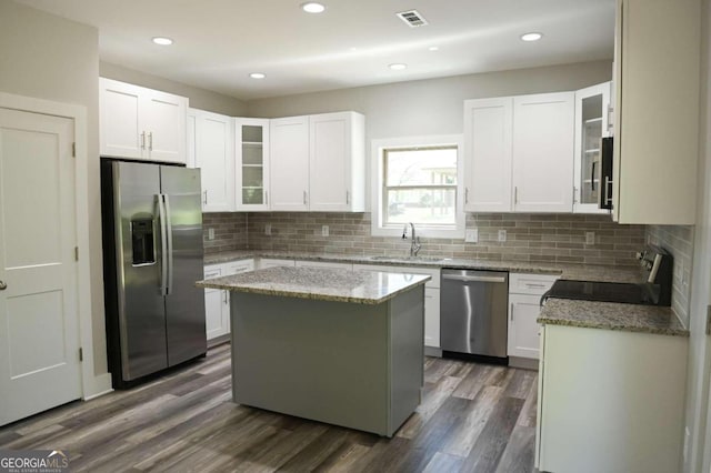 kitchen with appliances with stainless steel finishes, a kitchen island, white cabinetry, and sink