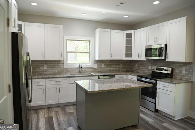 kitchen featuring light stone counters, a kitchen island, dark wood-type flooring, white cabinetry, and stainless steel appliances