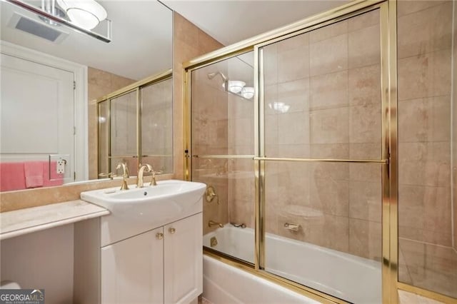 bathroom featuring oversized vanity and shower / bath combination with glass door