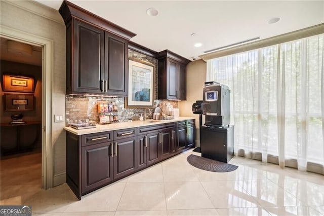 kitchen featuring dark brown cabinets, tasteful backsplash, and light tile floors