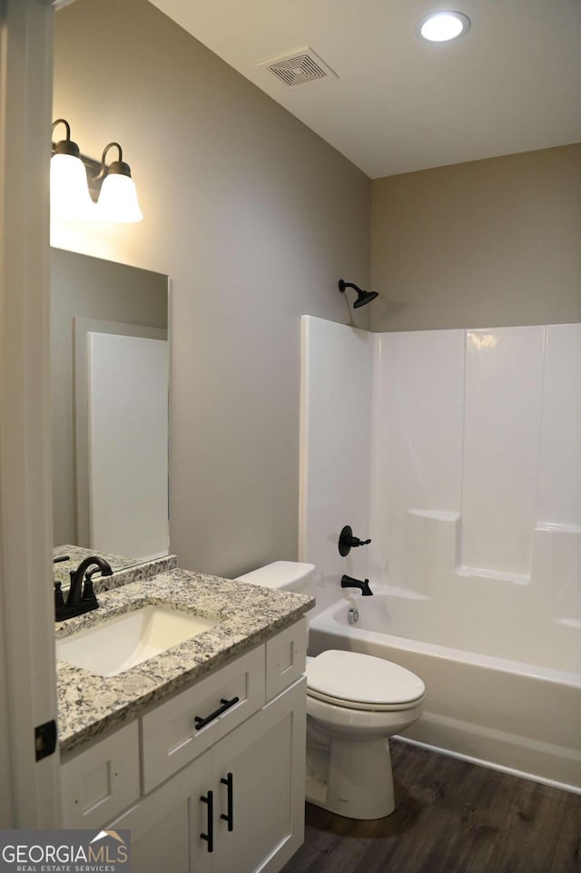 full bathroom featuring hardwood / wood-style floors, shower / bathtub combination, vanity, and toilet