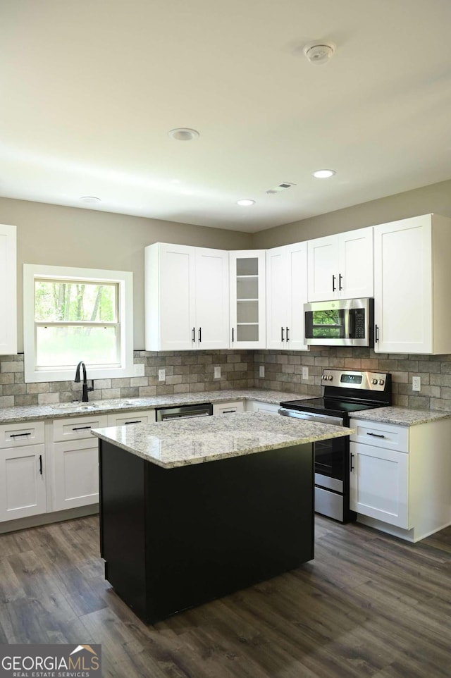 kitchen featuring backsplash, white cabinets, stainless steel appliances, and dark hardwood / wood-style floors