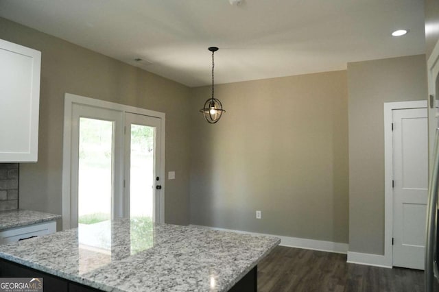 interior space with dark wood-type flooring, hanging light fixtures, white cabinetry, and light stone countertops